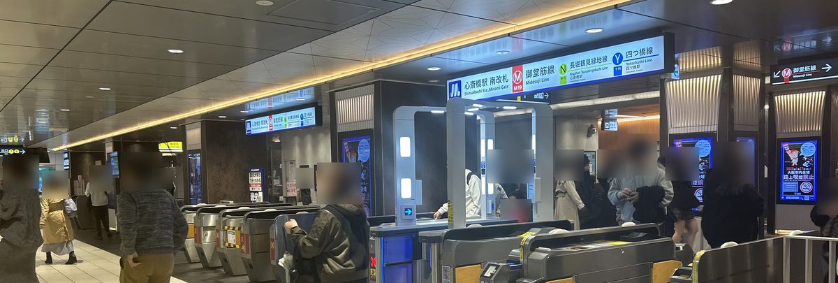 心齋橋站的一排自動驗票閘門，上方藍白色指標寫著心斎橋駅 南改札，旁邊並列御堂筋線、長堀鶴見綠地線、四つ橋線三條路線