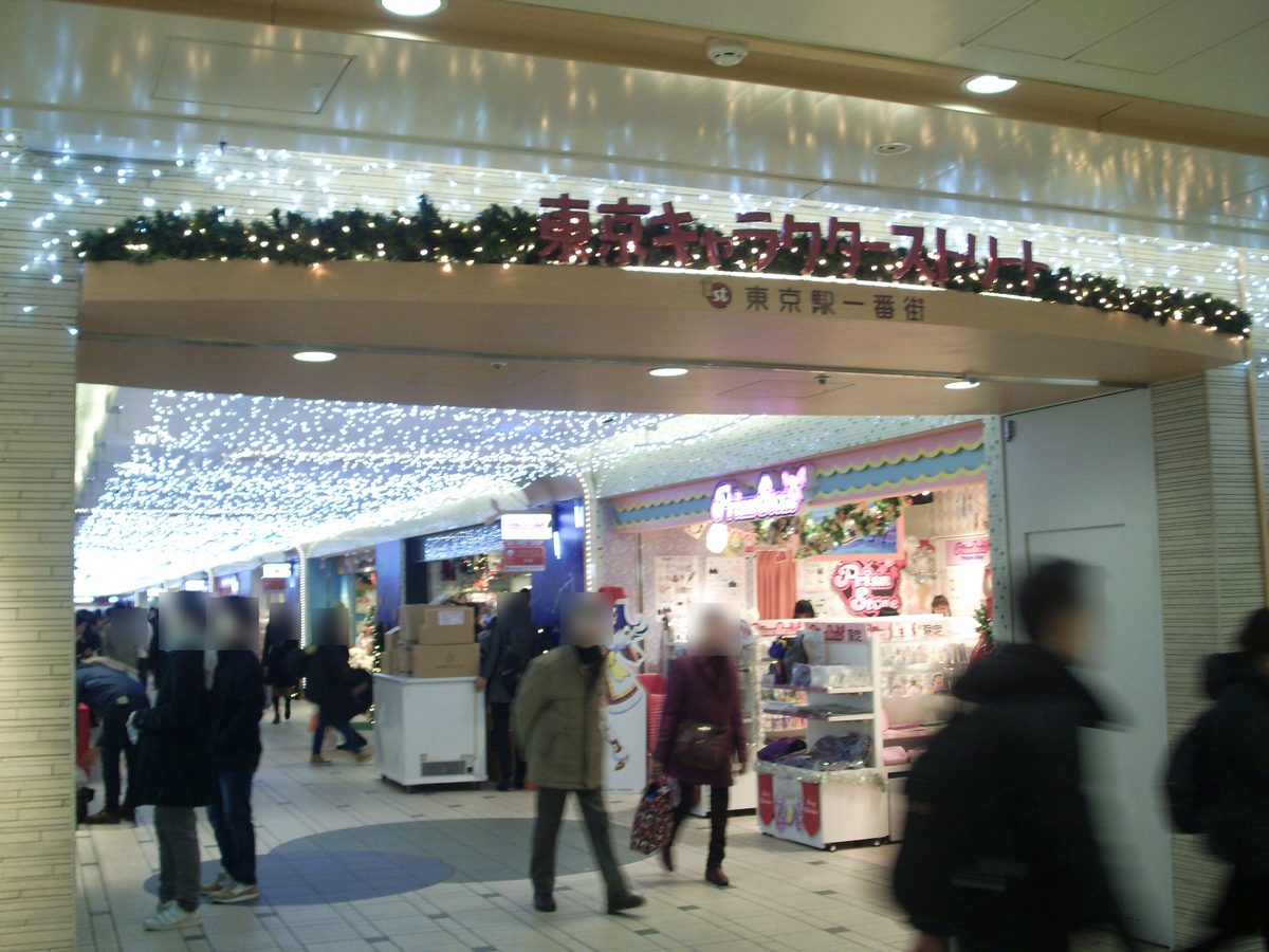 東京車站一番街的東京角色街入口：拱門上方紅字寫著東京キャラクターストリート、下面是東京駅一番街，通道天花板掛滿白色燈飾，兩側是商店