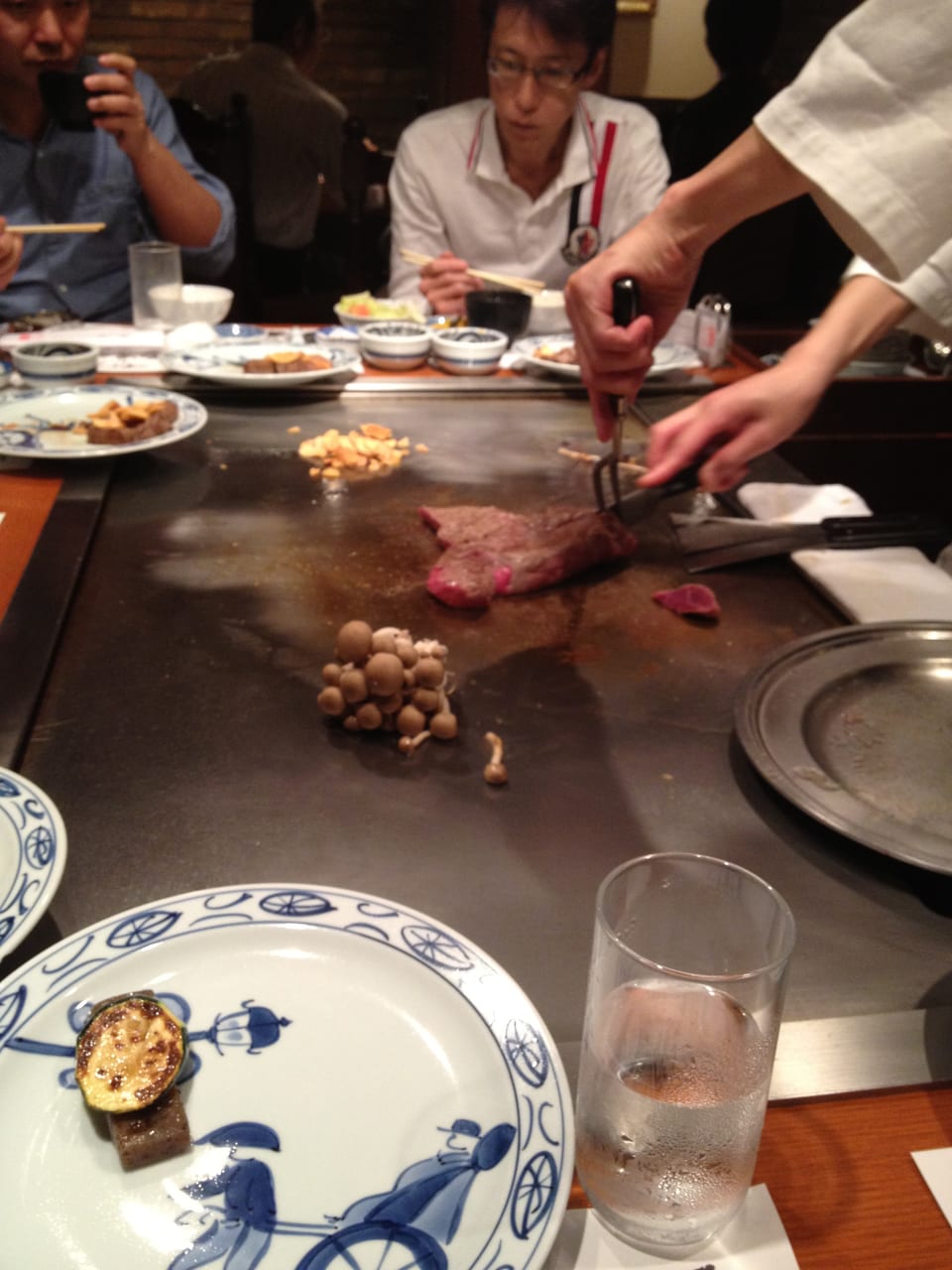 A chef searing a Kobe beef steak on the teppanyaki griddle