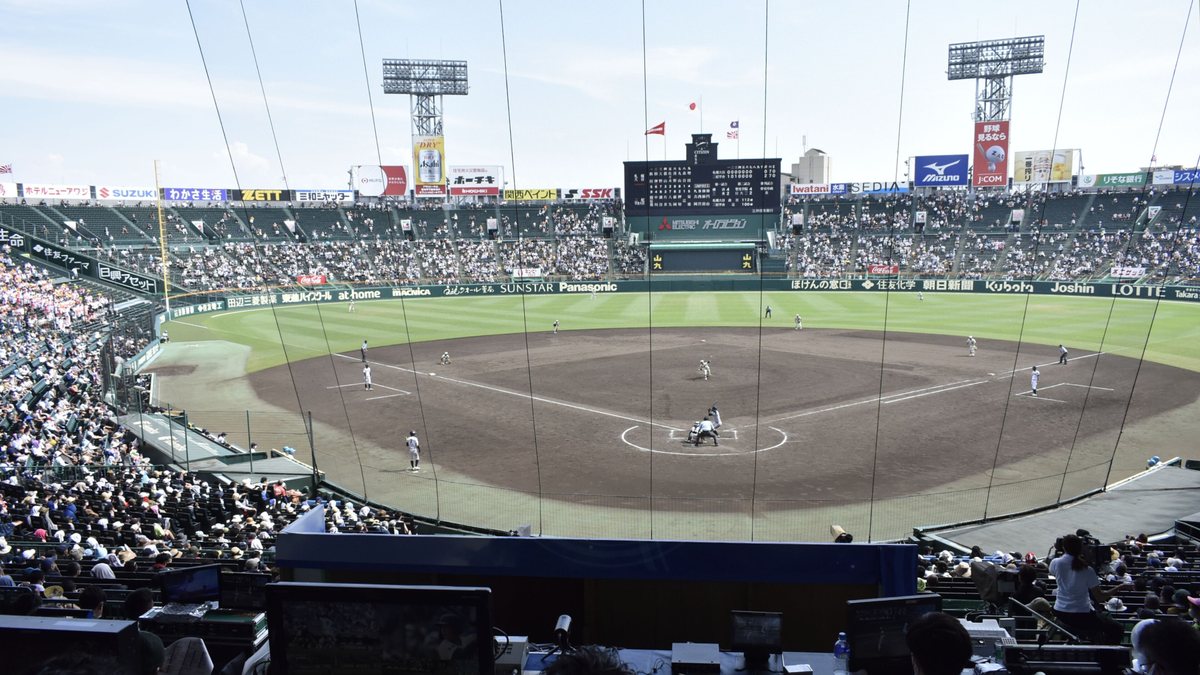 players in white uniforms on the field, the stands filled with spectators and the scoreboard showing the game in progress