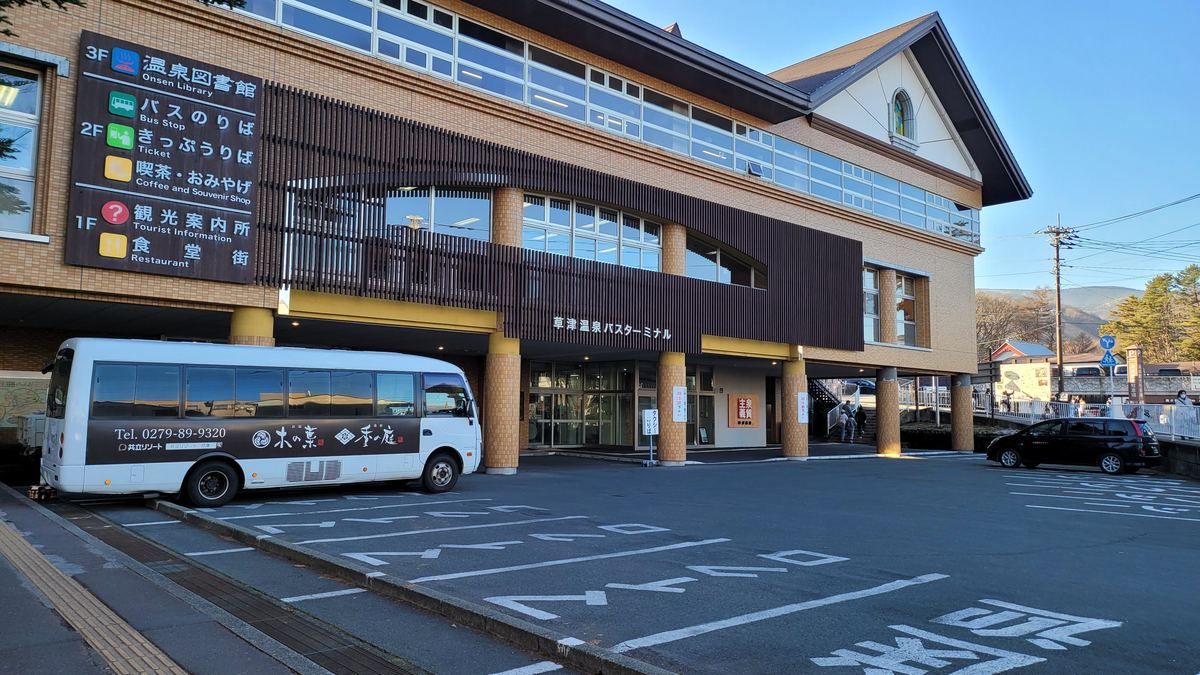 草津溫泉巴士總站外觀,牆上樓層看板寫著 3F 溫泉圖書館、2F 巴士乘車處與售票處、1F 觀光案內所與食堂