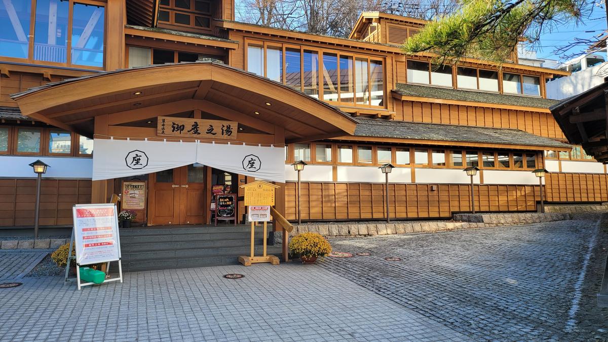 御座之湯正面,木造兩層建築,入口掛著印有「座」字的白色暖簾