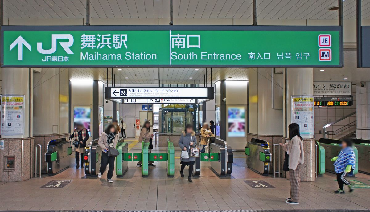 JR 舞浜站南口的閘門,上方綠色大看板寫著舞浜駅 Maihama Station 與南口 South Entrance,閘門內外有幾名旅客(臉部已打馬賽克)