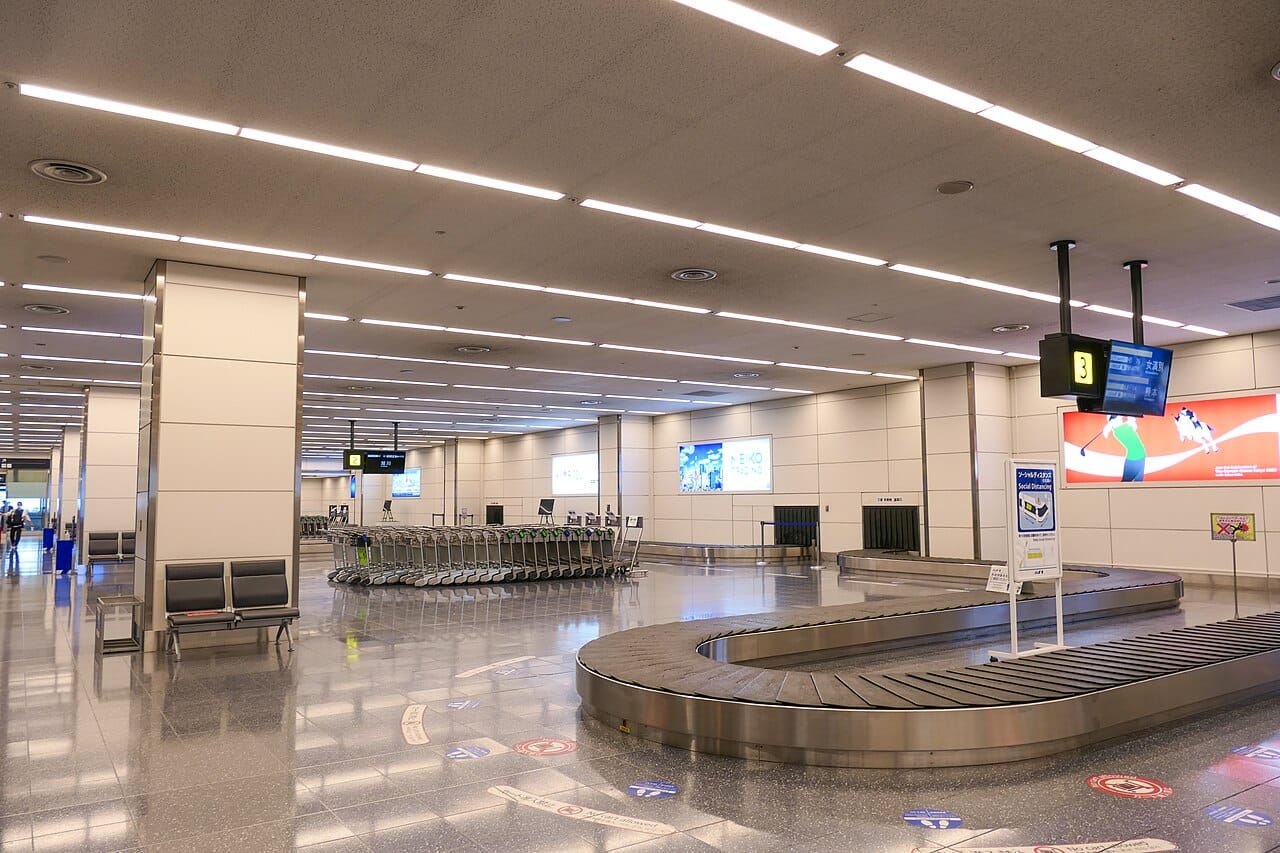 Baggage claim carousel at Haneda Airport Terminal 2, travellers waiting to collect checked luggage before clearing customs
