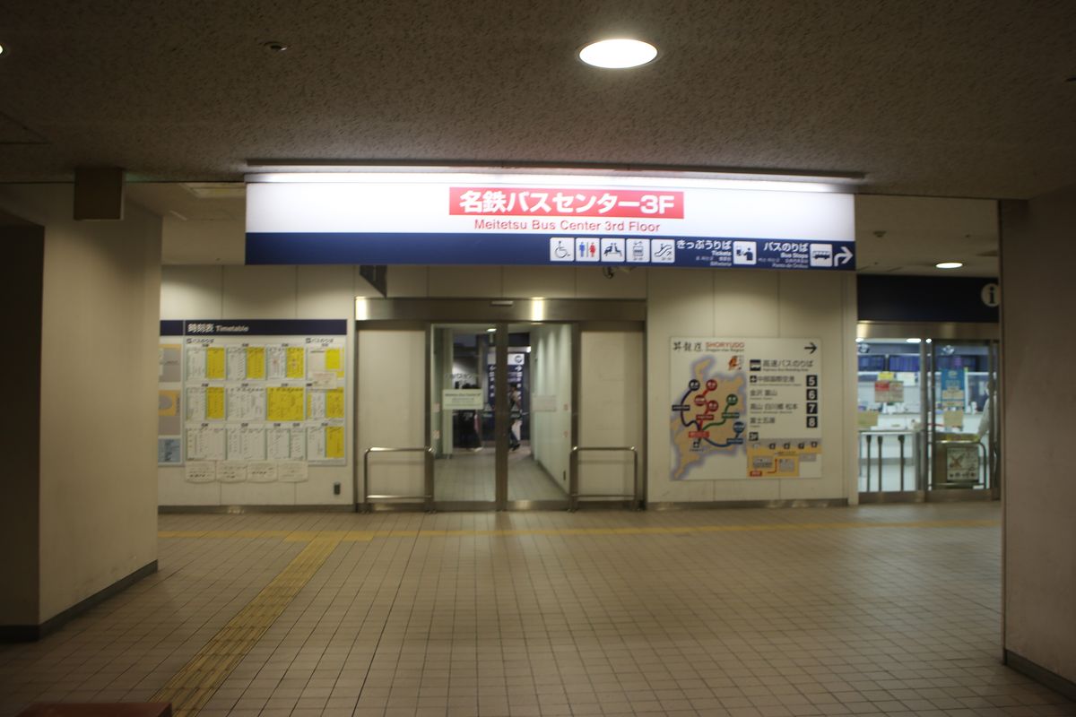 名鐵巴士中心 3 樓入口:上方紅底白字看板「名鉄バスセンター3F Meitetsu Bus Center 3rd Floor」,旁邊指標寫きっぷうりば、バスのりば;玻璃門左邊是時刻表牆,右邊導覽板列出高速巴士乘車處:中部國際空港 5、金沢・富山 6、高山・白川郷・松本 7、富士五湖 8