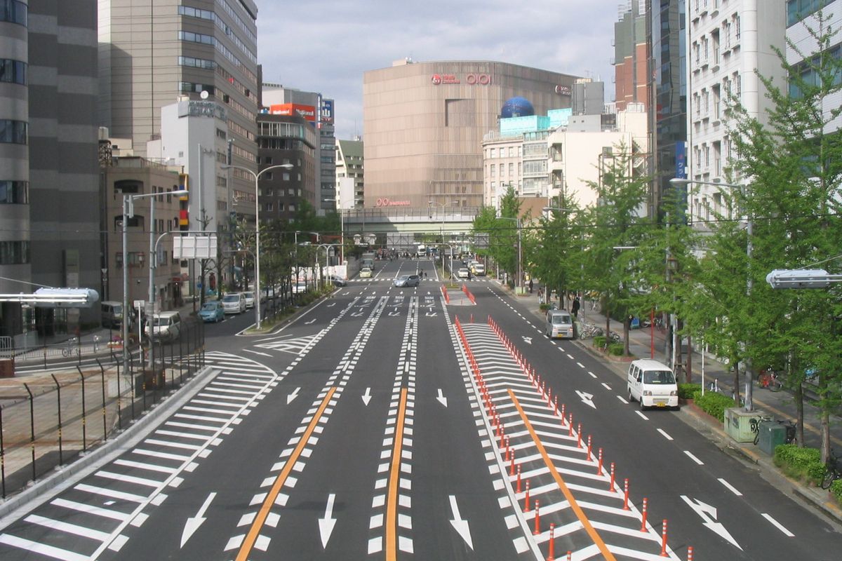 Midosuji in daylight from a footbridge at its southern end, the straight multi-lane boulevard and its street trees running north back towards Namba