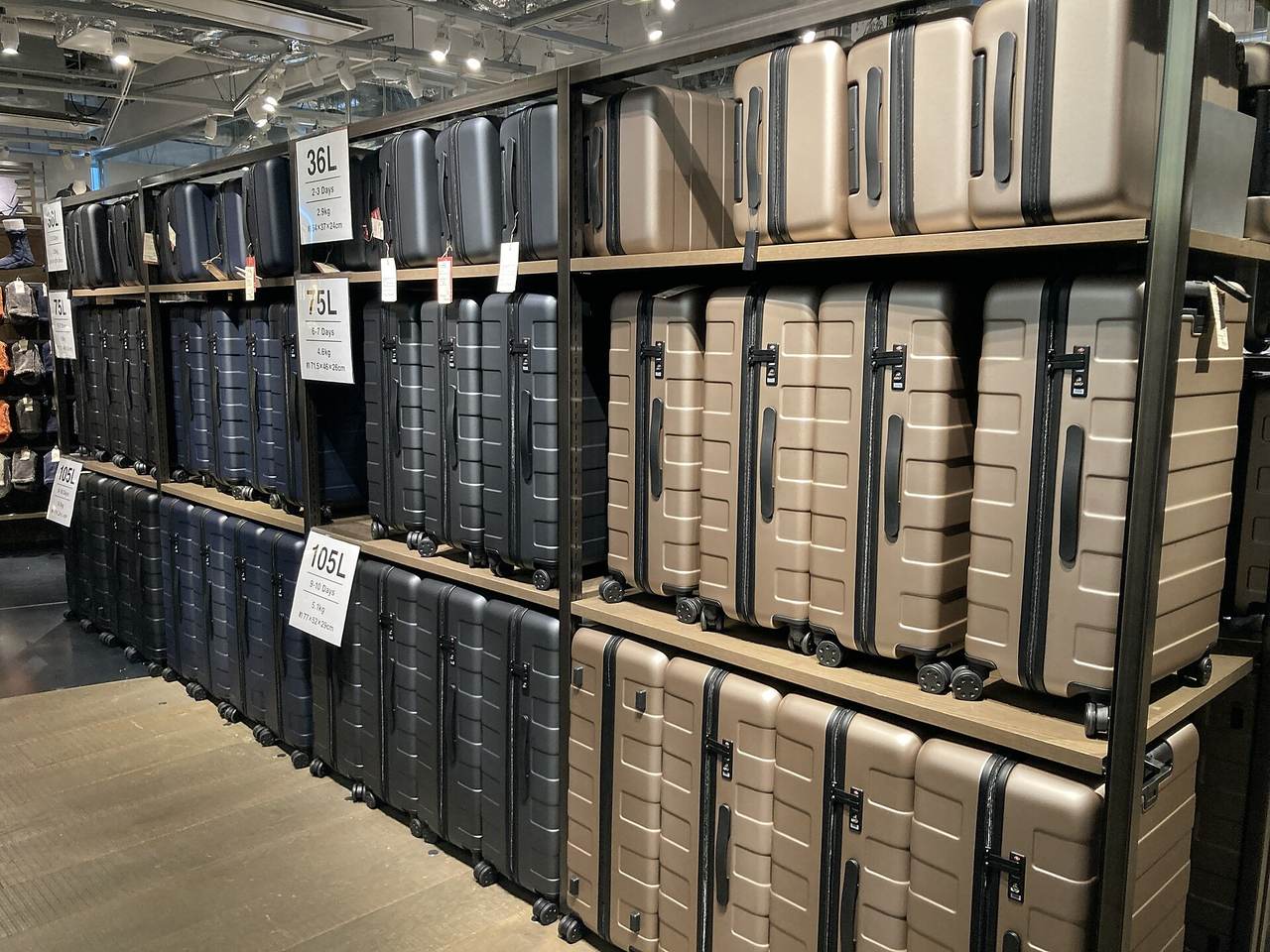 The luggage wall inside the MUJI Ginza world flagship store, its shelf cards giving capacity and trip length rather than prices