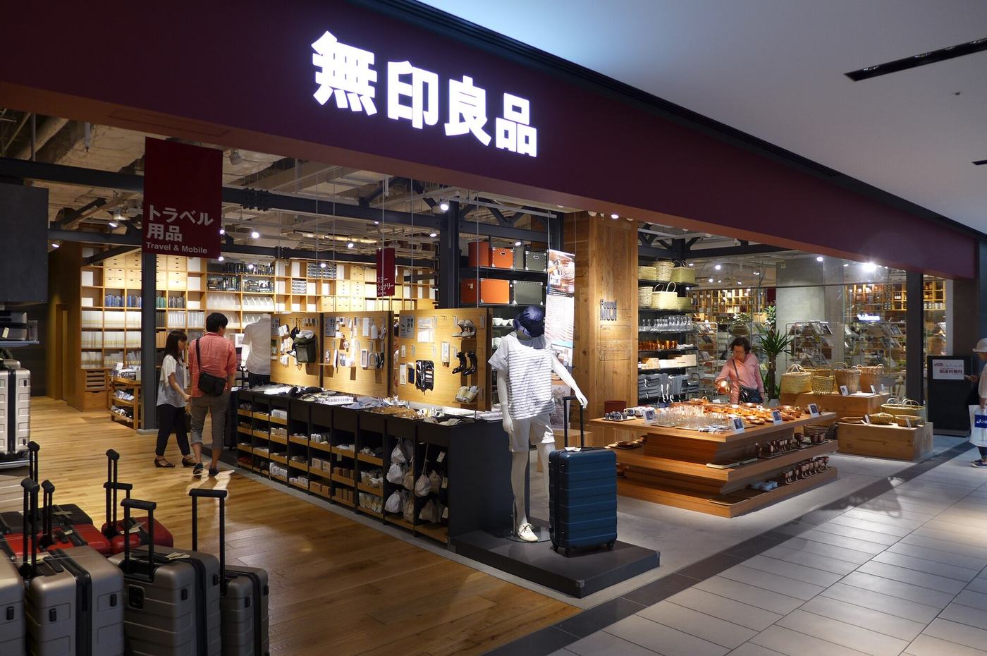 Household goods displayed on pale wooden shelving inside a MUJI store