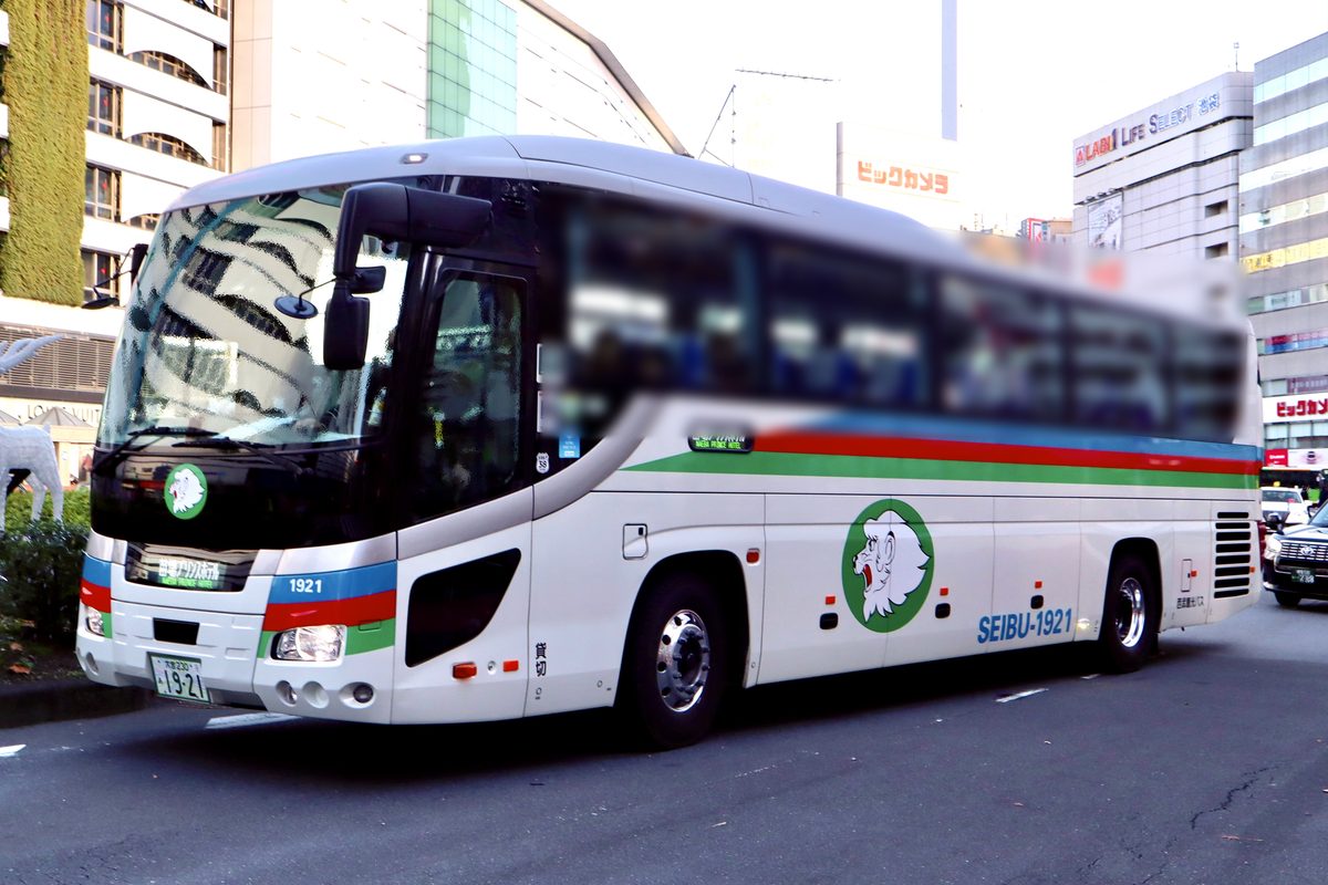 西武観光バス的白色高速巴士停在池袋站東口,車身有藍紅綠三色線條和獅子圖案,車頭與車側的行先顯示寫著「苗場プリンスホテル」