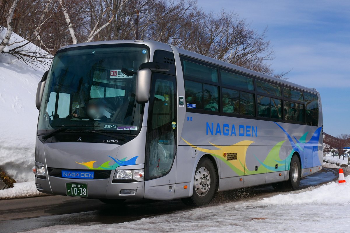 雪地路旁一輛銀色車身、側面印著藍字 NAGADEN 的長電巴士,擋風玻璃內的方向牌寫「急行 長野駅 NAGANO STA.」