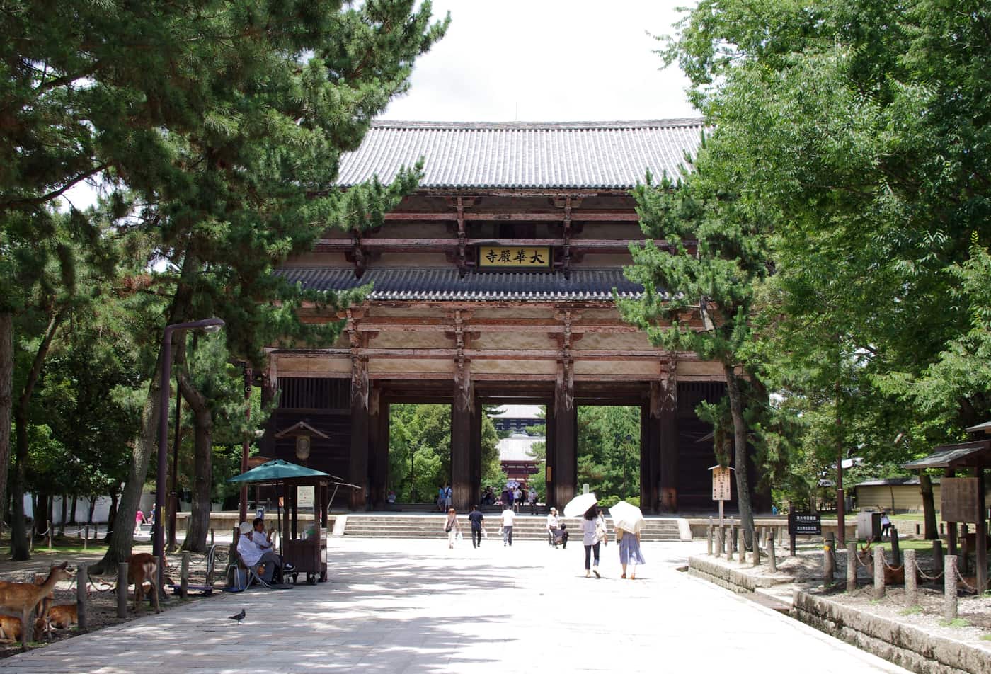 The Great South Gate of Todaiji with visitors on the approach and deer resting in the shade beside it