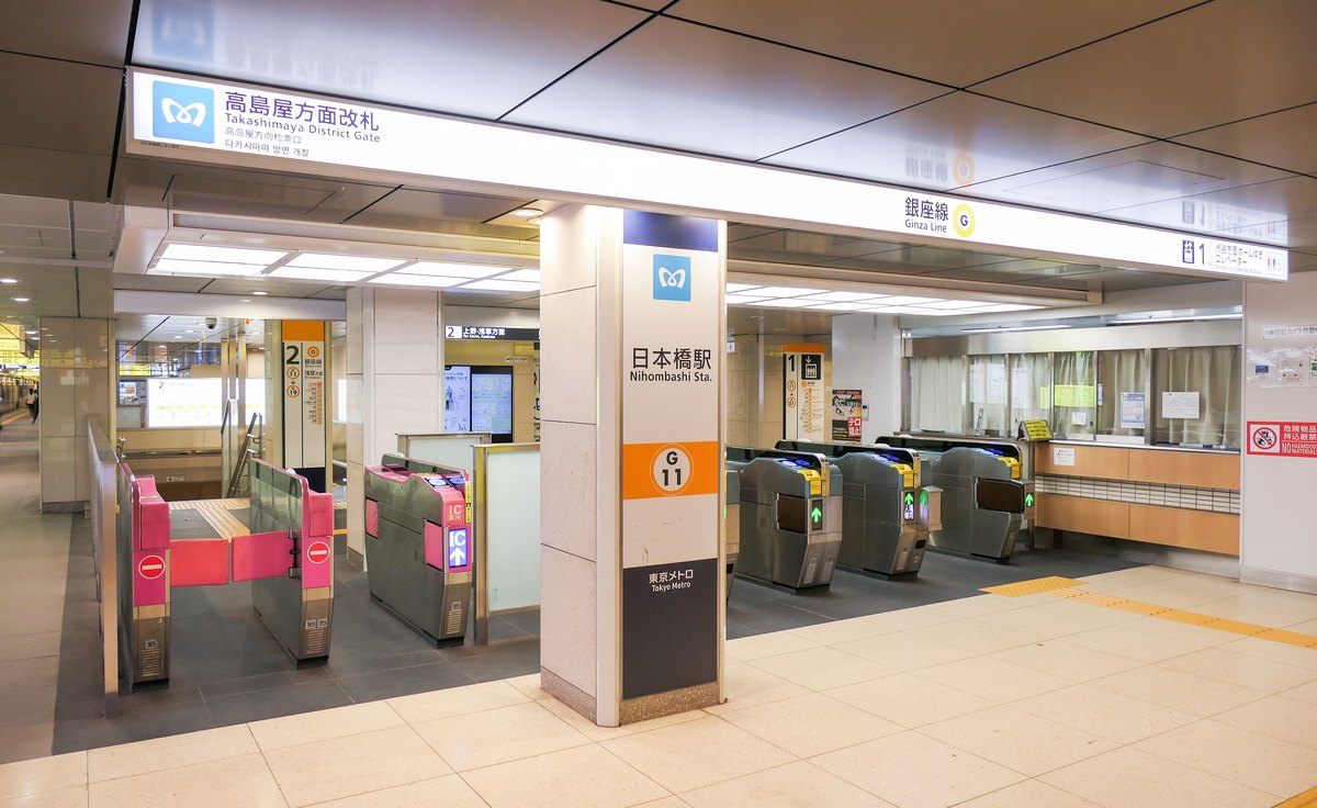 東京 Metro 日本橋站銀座線的高島屋方面改札:頭頂白色燈箱寫著高島屋方面改札 Takashimaya District Gate 與銀座線,中間柱子上是日本橋駅 G11 的站名牌,前面一排自動驗票閘門