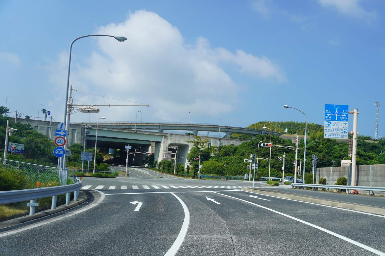 淡路IC 前的一般道路路口,高架匝道下方立著藍色指標,寫著直走 2.3 km 是県立淡路島公園、左轉 1.5 km 是淡路島国際公園都市