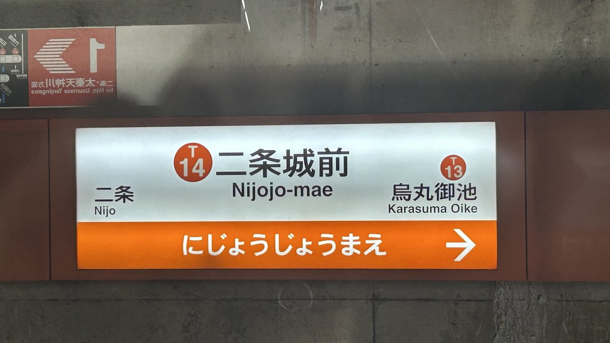 地下鐵東西線二条城前站月台的站名標:白底寫「二条城前 Nijojo-mae」,站號 T14,左邊下一站二条、右邊烏丸御池 T13,下方橘色條寫平假名站名