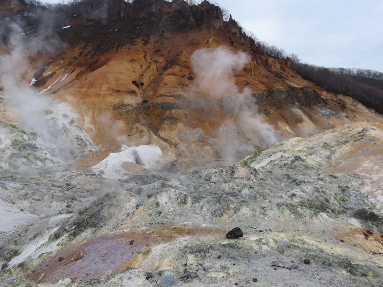The volcanic crater terrain of Noboribetsu Hell Valley, venting white sulfur steam over a boardwalk