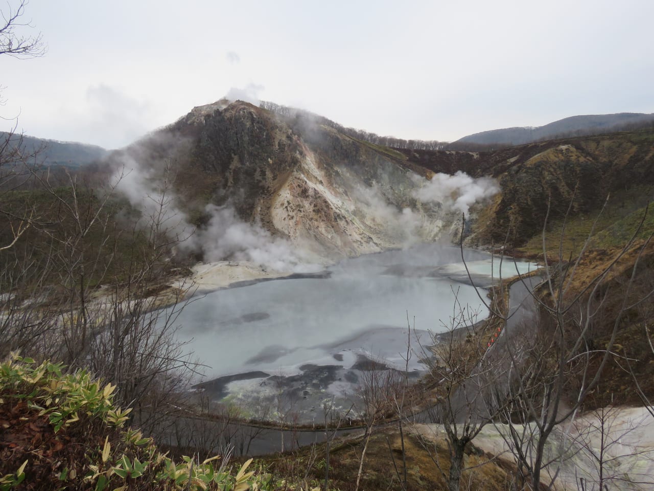 Oyunuma pond at Noboribetsu, a dark gray sulfur hot pond formed in a volcanic vent, steaming