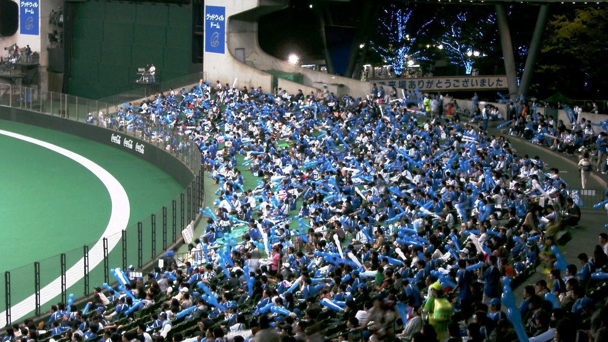 a whole stand of supporters in the same team colour, holding the jet balloons released in the seventh inning