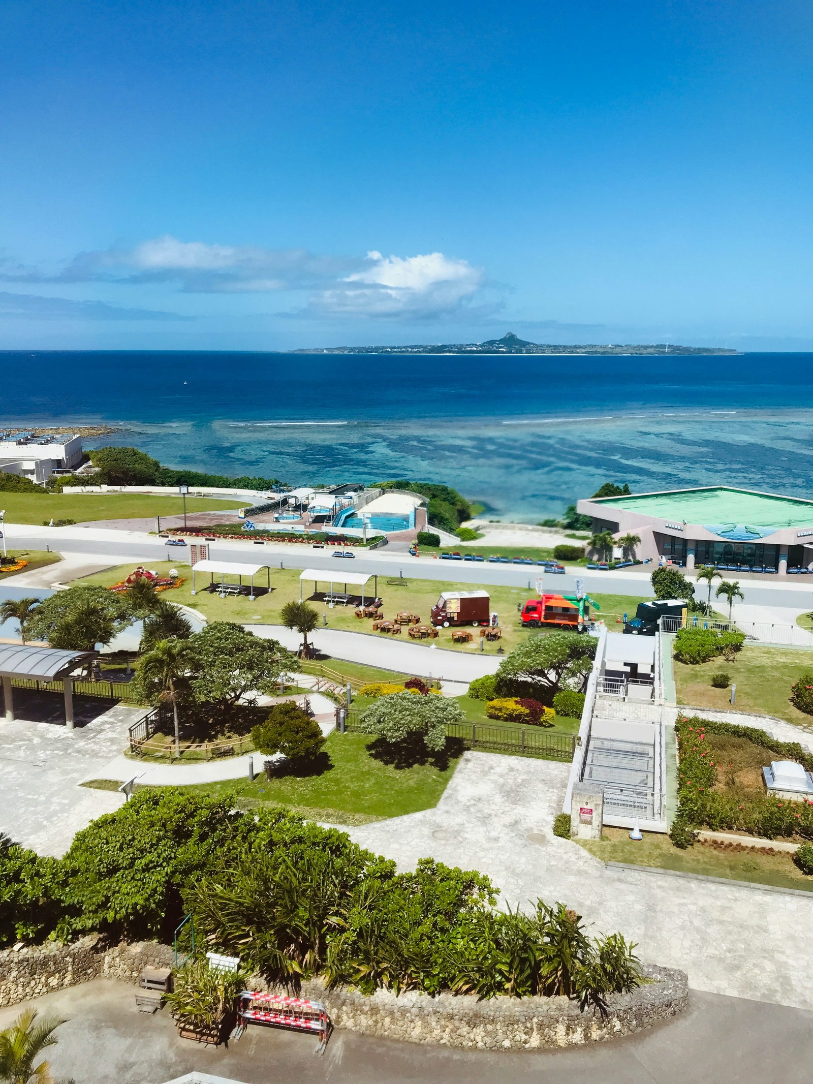 Okinawa coastal highway with turquoise ocean and a white rental car driving along the shore