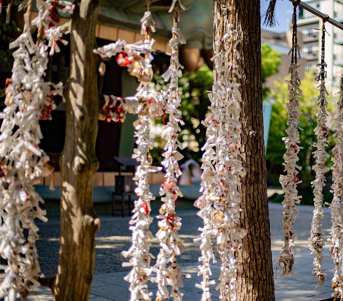 A shrine musubidokoro rack hung with thousands of folded white omikuji slips, forming curtains of paper