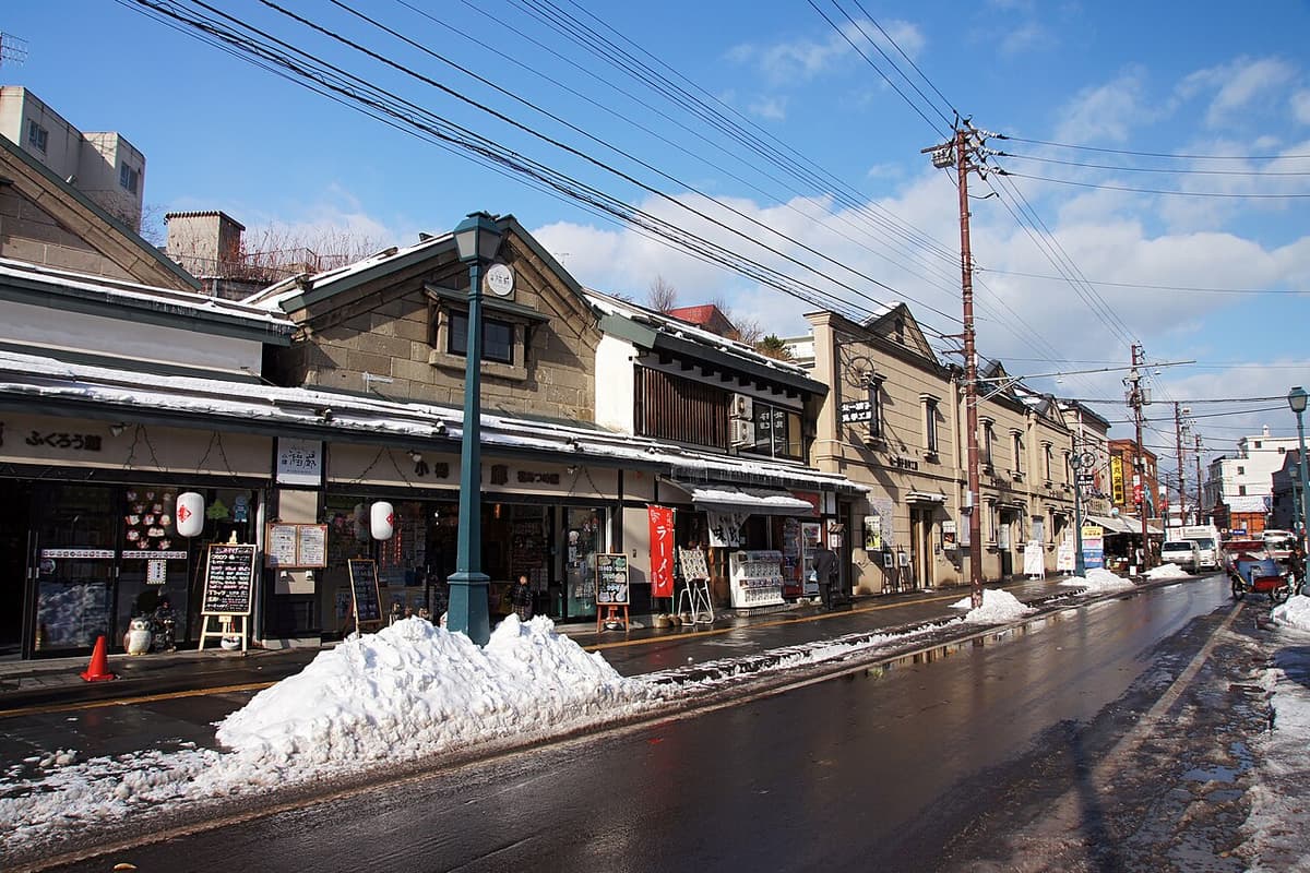 Otaru's Sakaimachi shopping street in daylight, historic stone buildings lining the street