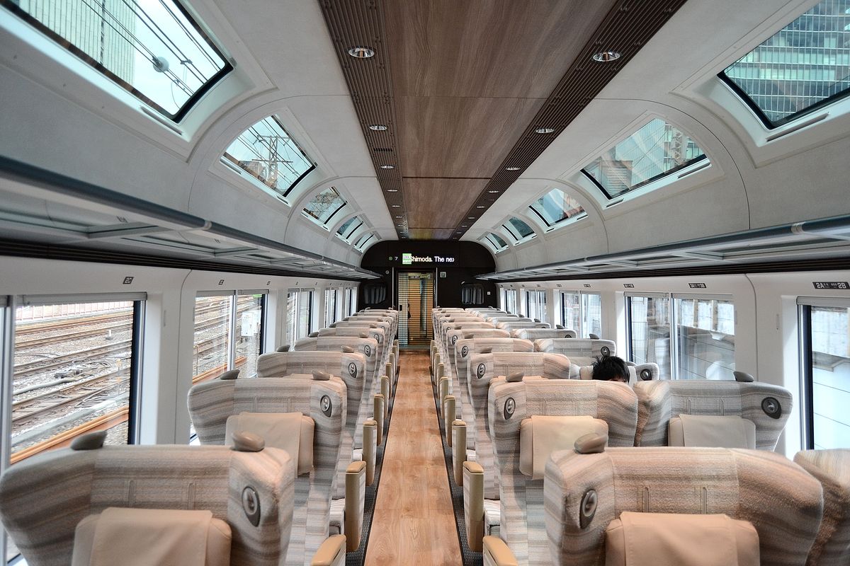 SAPHIR 踴子號綠色車廂內部:米灰條紋布面座椅排列在木紋地板走道兩側,車頂兩側各有一整排斜向的天窗,側窗很大,車廂盡頭的電子看板亮著