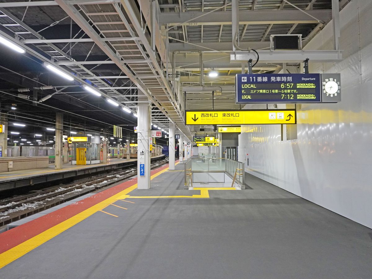 JR 札幌站 11 號月台，上方發車看板寫「11番線 発車時刻」，兩班 LOCAL 普通車的終點都是 HOKKAIDO-IRYODAIGAKU（北海道医療大学），旁邊黃色指標寫西改札口、東改札口