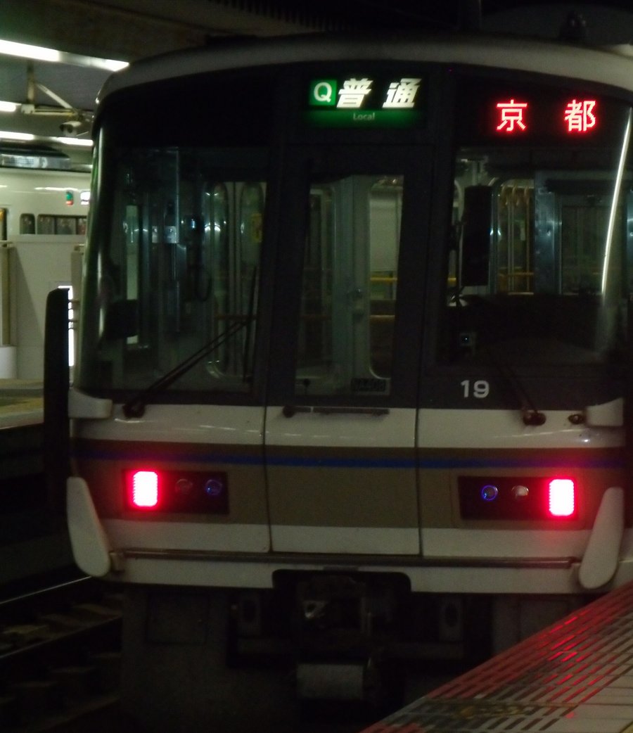 夜間奈良站月台上的 JR 西日本 221 系電車正面：車頭上方綠底看板寫「普通」，右邊紅色字幕顯示「京都」