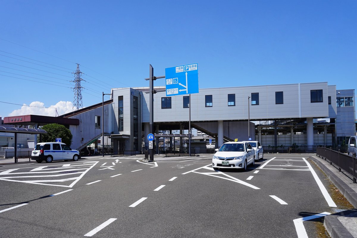 JR 中野榮站南口:灰白色高架站房下是站前圓環,停著兩輛白色計程車,藍色路標寫著「一般車」「P 駐車場」並用箭頭指出「バス」「タクシー」乘車處的方向,晴天、幾乎沒有人