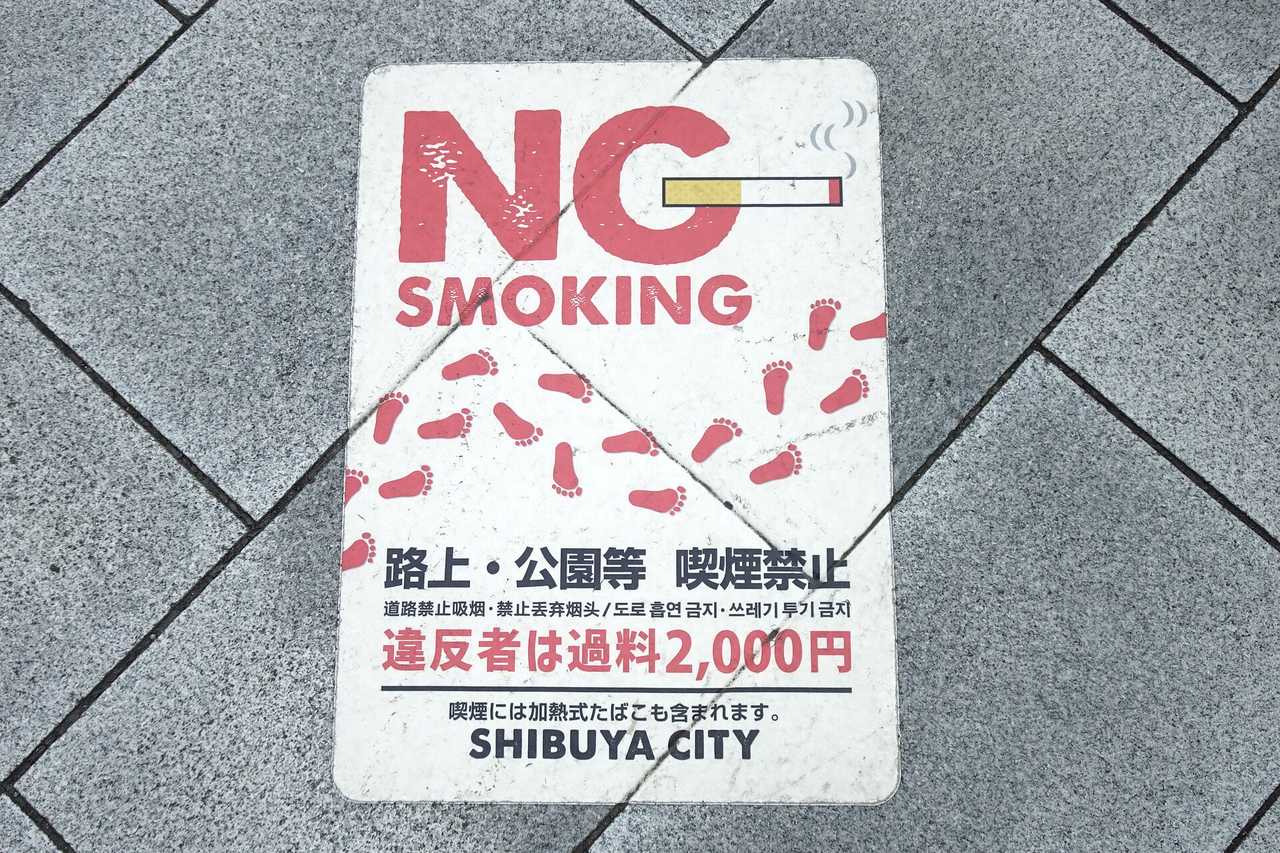 A NO SMOKING decal set into a Shibuya pavement reading no smoking on streets and in parks, with a 2,000 yen fine for offenders