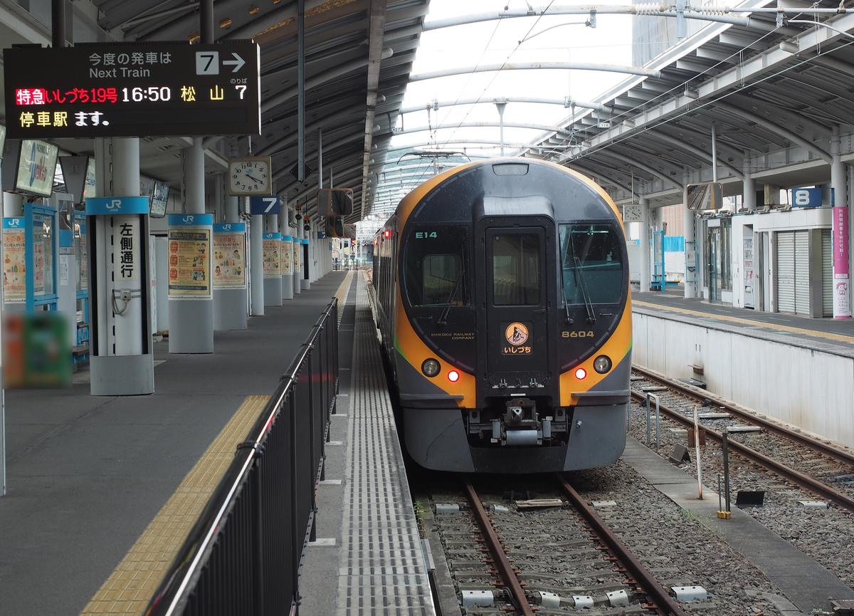 高松站 7 號月台,一列黑底橘色車頭的 8600 系電車停在月台邊,車頭標誌寫著「いしづち」,左上的發車看板寫著「特急いしづち19号 16:50 松山 7」,月台柱子上掛著「左側通行」的牌子
