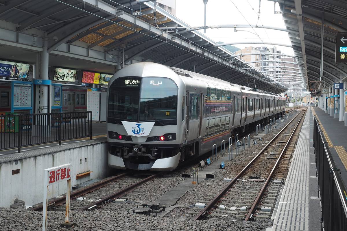 高松站月台旁停著一列快速 Marine Liner,銀白色車頭的行先顯示寫著「快速マリンライナー」與「岡山」,車頭貼著藍色的「3億人」紀念標誌,左邊月台角落立著紅字「通行禁止」的白色牌子