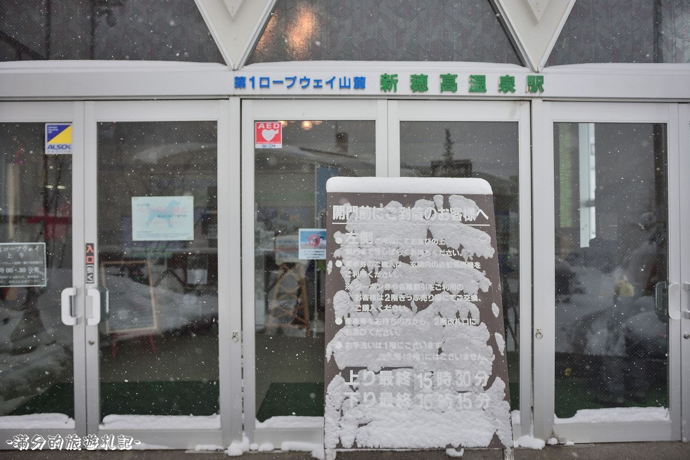 新穗高溫泉站第 1 纜車山麓站的自動門外,一塊積著雪的告示牌下半寫著「上り最終 15時30分」「下り最終 16時15分」