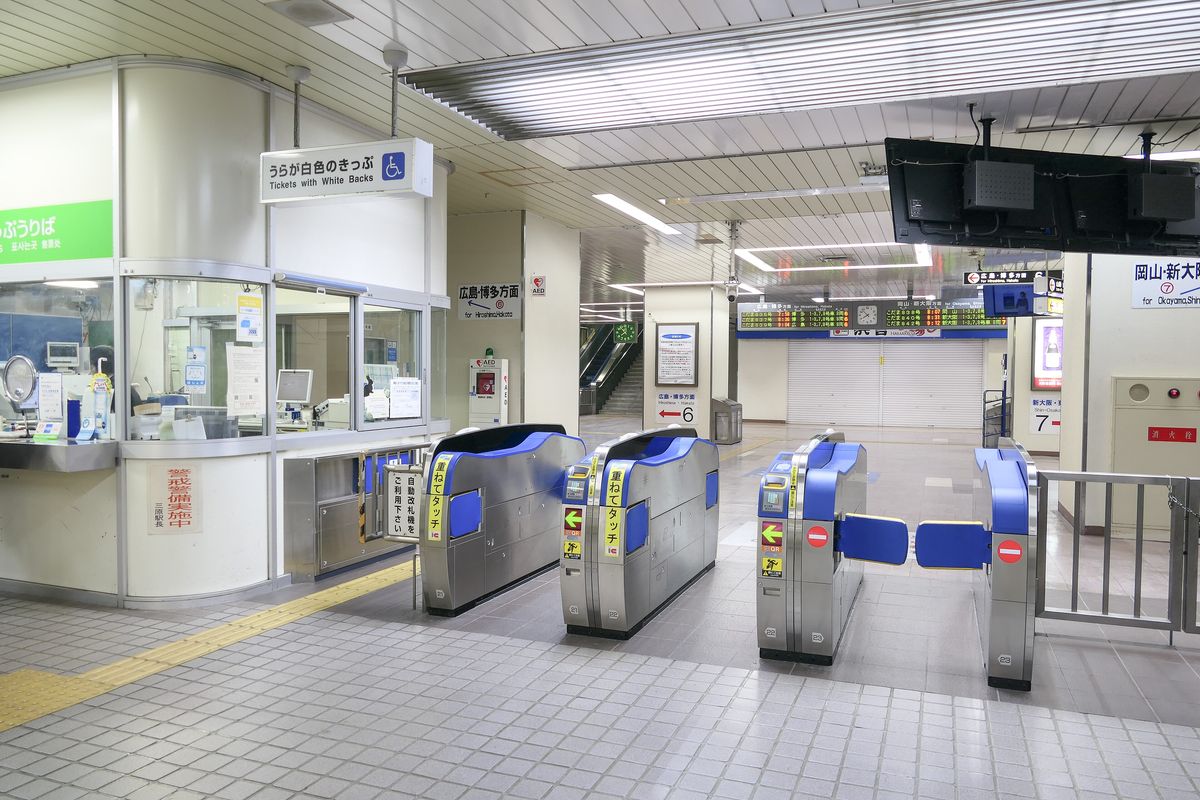 The Shinkansen transfer gates at JR West Mihara Station, each blue gate carrying a yellow kasanete-touch IC reader sticker, with green arrows showing the open direction