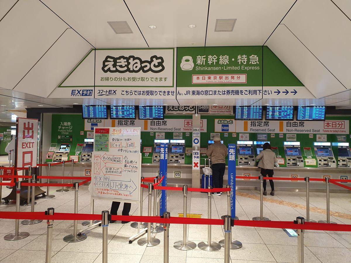 The JR East Shinkansen and limited express ticket machines at Tokyo Station, split into reserved and non-reserved rows, under a banner stating that EX Reservation and Smart EX bookings cannot be collected here and directing passengers to JR Central counters and machines