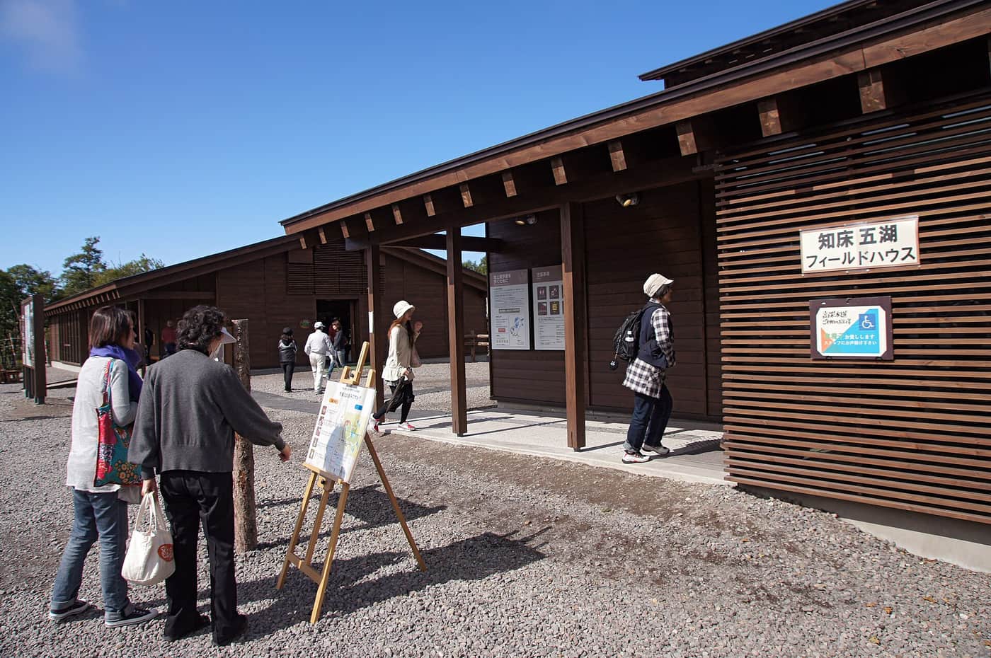 The dark timber Shiretoko Goko Field House building with its entrance signboard and visitors outside