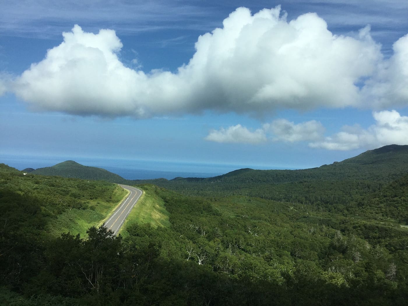 Route 334, the Shiretoko Crossing Road, winding downhill near Shiretoko Pass with the Sea of Okhotsk beyond
