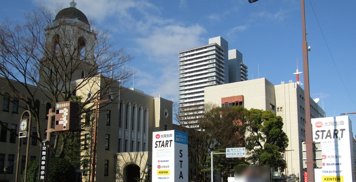 2025 年靜岡馬拉松起跑當天早上的靜岡市役所前:左邊是圓頂塔樓的市役所本館,路中間和右邊立著寫有 START 的白色贊助看板,背景是高樓與藍天