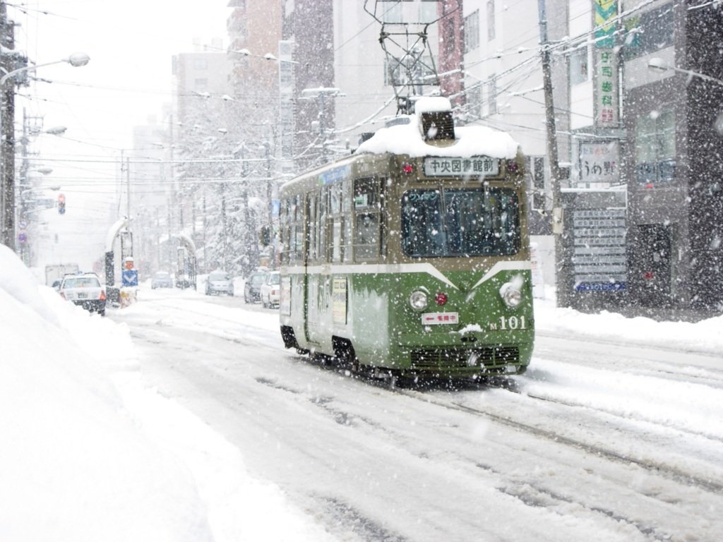 大雪中的札幌市電:一台綠白色舊型電車車頂積著厚雪,方向幕寫「中央図書館前」,車頭編號 M101,路面與兩側人行道都被雪蓋住