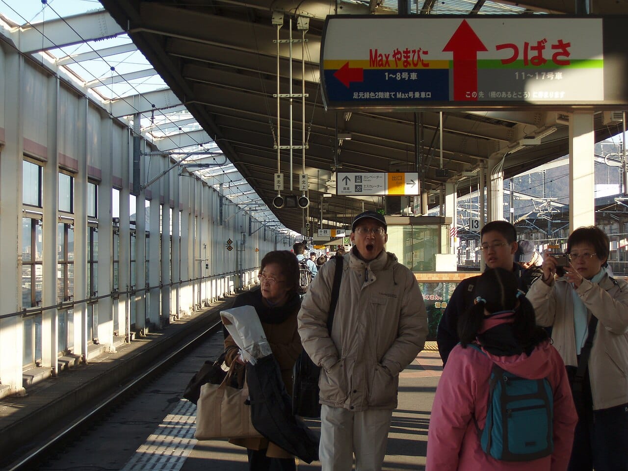 A solo traveler waiting alone on a Japanese Shinkansen platform, where clear signage and punctual trains make solo navigation easy
