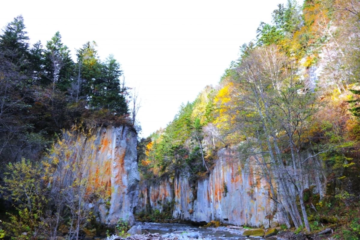 Ryusei (Shooting Star) Falls and Ginga (Galaxy) Falls side by side framed by basalt columns and autumn maples, Sounkyo Gorge
