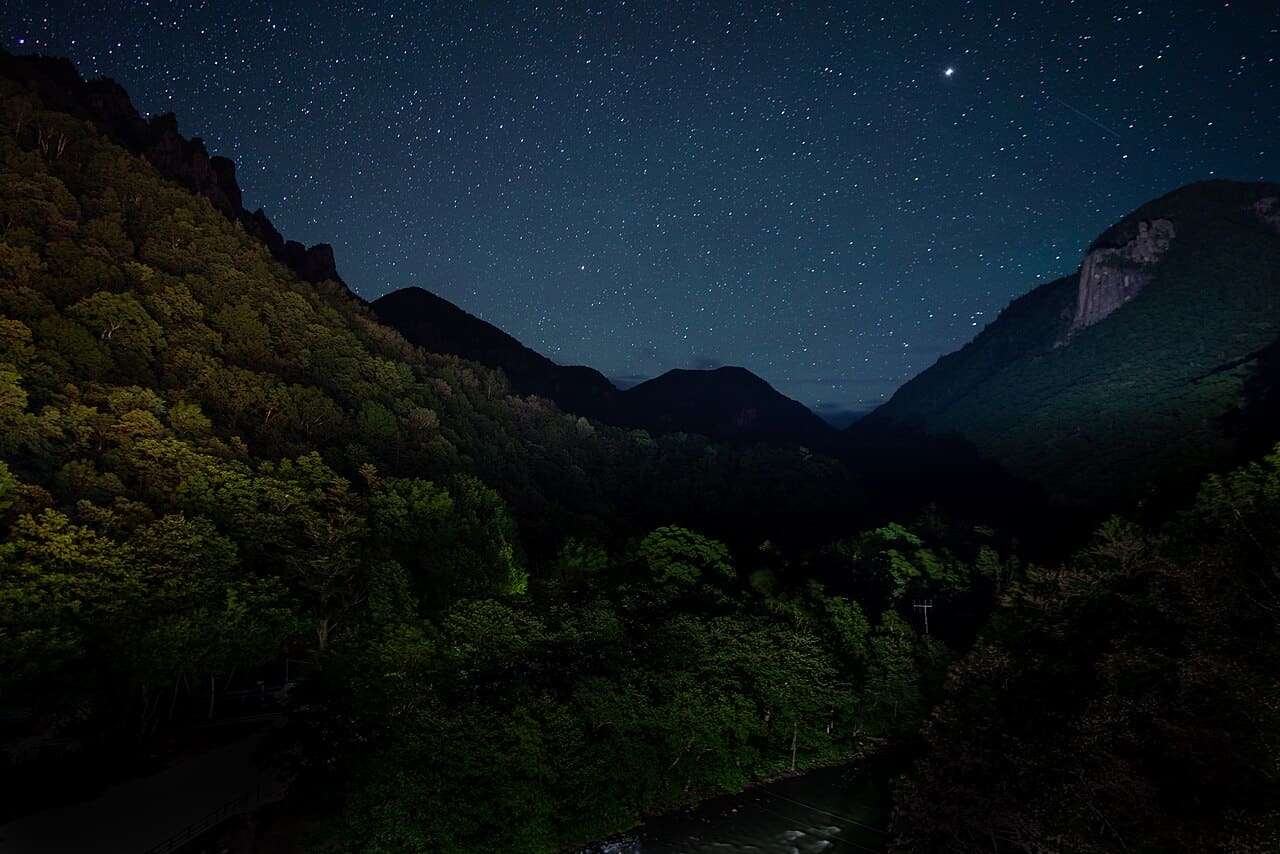 Star-filled summer night sky over Sounkyo Canyon, with the dark silhouettes of the gorge walls below