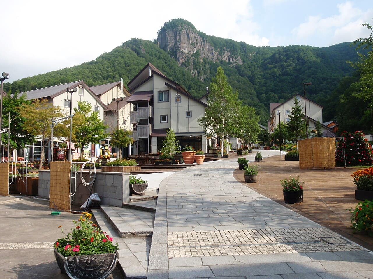 Stone-paved pedestrian street of Sounkyo Onsen with European-style buildings and a columnar rock peak behind