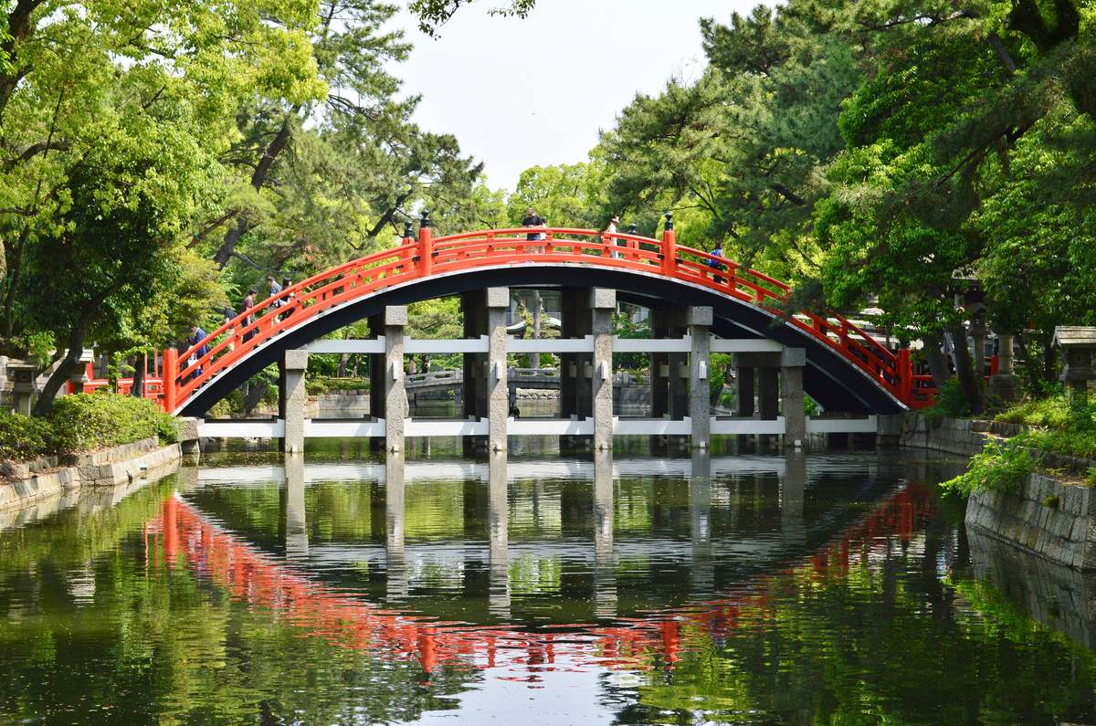 The steep vermilion arched Taiko-bashi bridge at Sumiyoshi Taisha shrine in Osaka reflected in the pond below