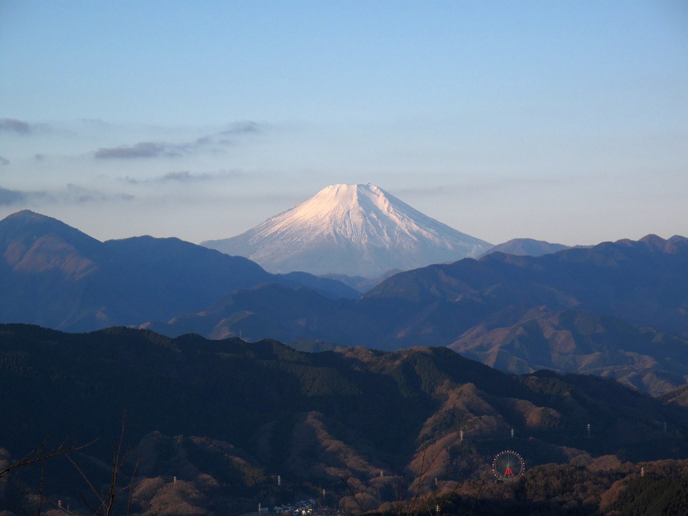 Snow-capped Mount Fuji seen from the summit of Mount Takao in winter, with bare ridgelines of the Tanzawa range in front