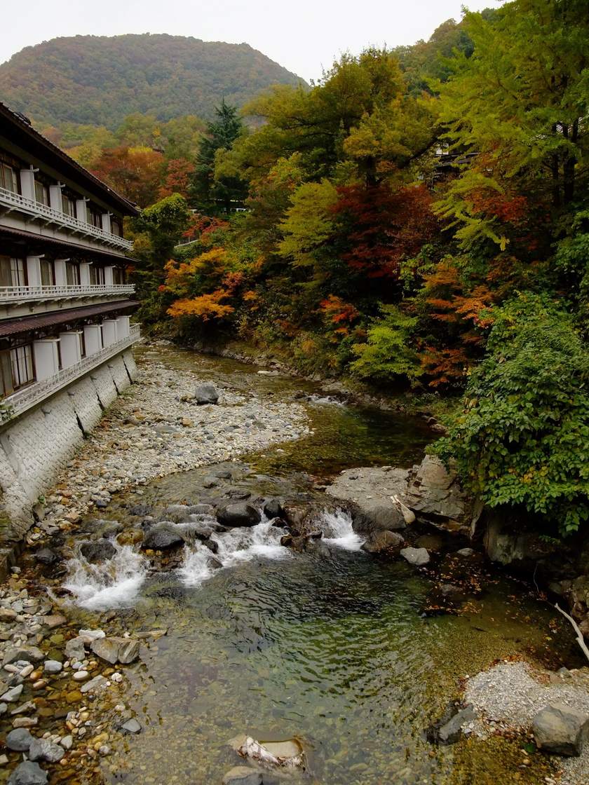 2009 年 10 月下旬的寶川溪谷：左岸是沿著石砌河堤蓋的多層旅館建物，右岸的樹紅、黃、綠夾雜，河床上是卵石與淺淺的急流
