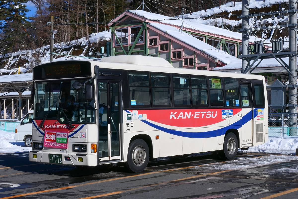 雪後的水上駅前，一輛紅藍白塗裝、車身印著 KAN-ETSU 的關越交通路線巴士，車頭掛著 PASMO 與 Suica 的牌子