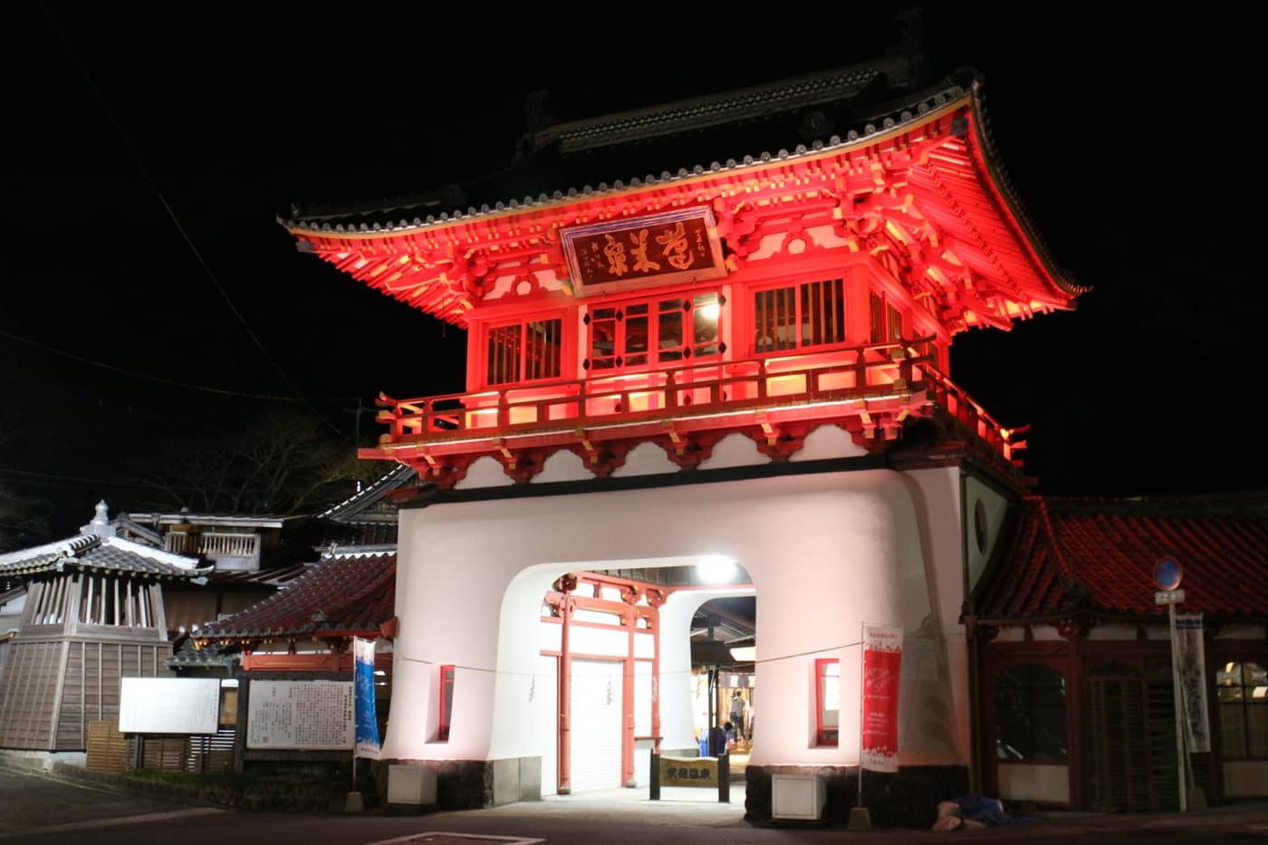 Takeo-Onsen romon gate illuminated at night, a vermilion ryugu-mon style gatehouse designed by Tatsuno Kingo, completed 1915, Takeo, Saga