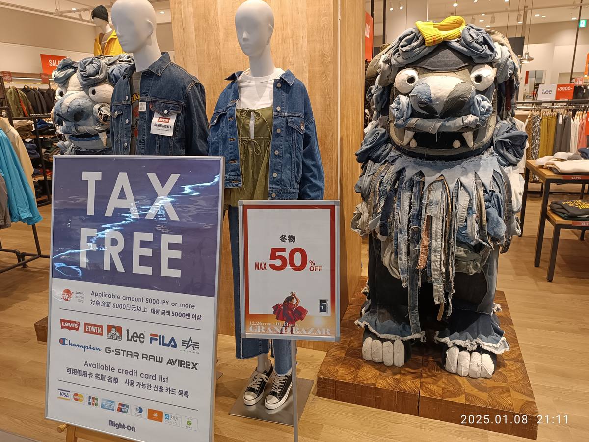 A TAX FREE placard on a Japanese mall shop floor stating the 5,000 yen minimum spend and accepted credit cards