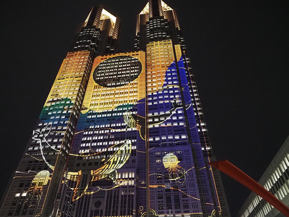 The twin towers of Tokyo Metropolitan Government Building No.1 lit by blue and yellow projection mapping, shot looking up at night