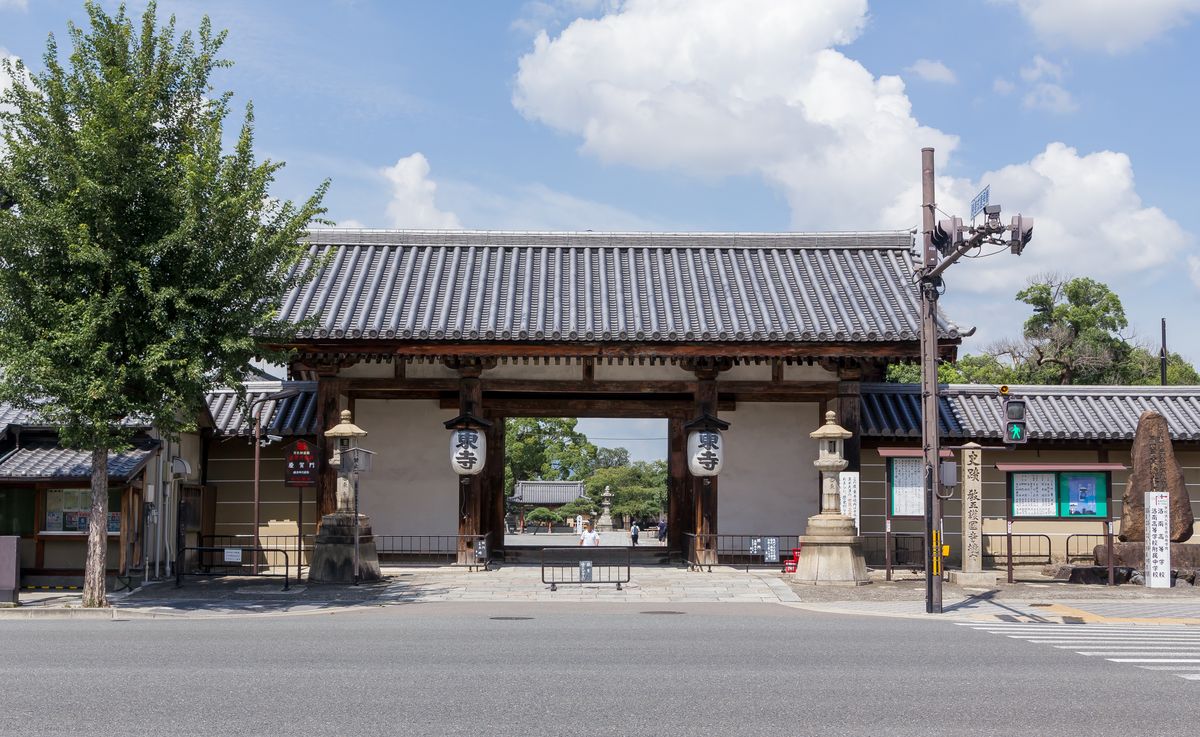 東寺慶賀門(東門)正面:瓦屋頂的木造門,門柱兩側掛著寫「東寺」的白燈籠,門前是大宮通的車道與行人號誌